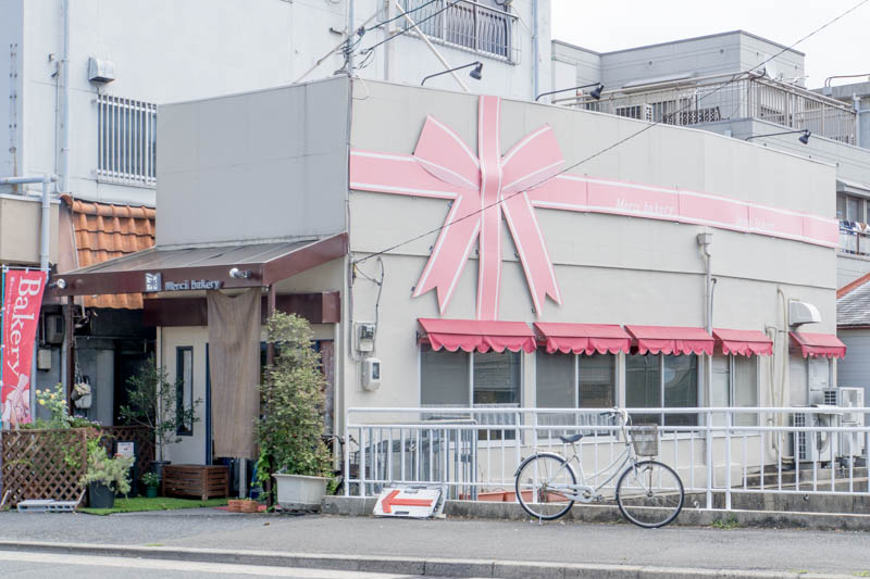 外観のリボンがかわいい「メルシーベーカリー」は徒歩約3分。食事パンから菓子パンまで個性的なパンが並びます。